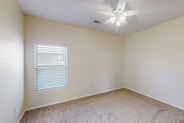 carpeted empty room featuring baseboards, visible vents, and a ceiling fan