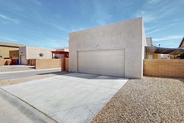 garage featuring concrete driveway and fence