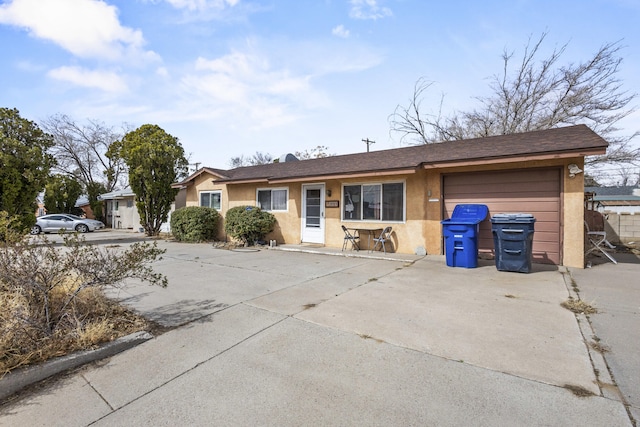 ranch-style house featuring a garage, concrete driveway, and stucco siding