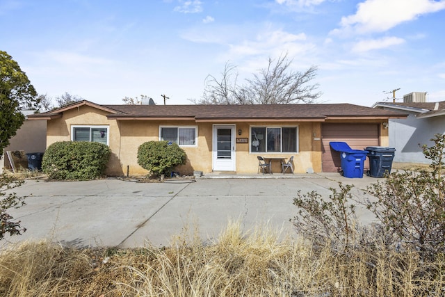 ranch-style house with a garage, central air condition unit, and stucco siding