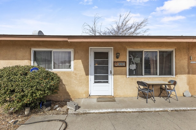 entrance to property with a patio and stucco siding