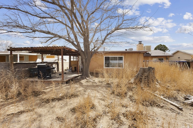 back of property featuring a chimney, fence, a wooden deck, and stucco siding