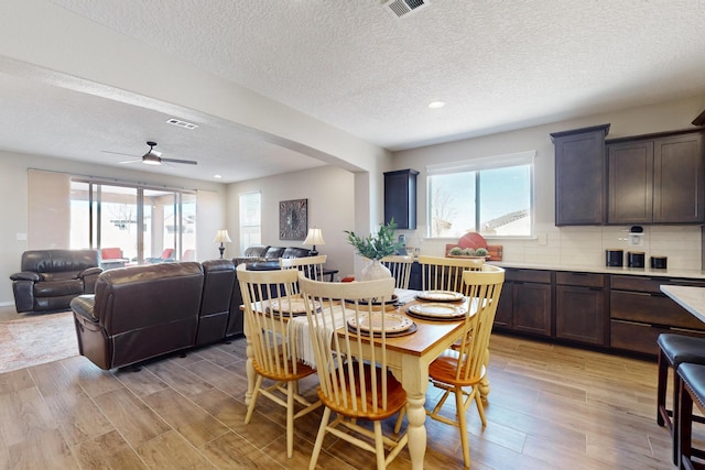 dining space featuring light wood-type flooring, arched walkways, visible vents, and ceiling fan