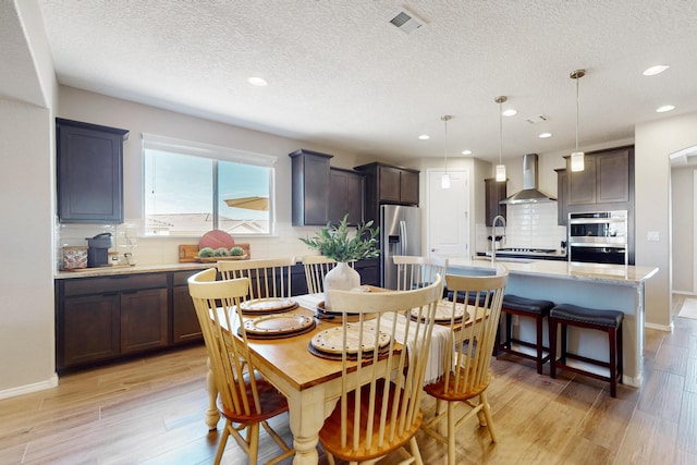 dining room featuring light wood-style flooring, visible vents, baseboards, and recessed lighting