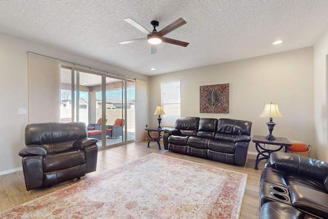 living room with baseboards, ceiling fan, a textured ceiling, light wood-style floors, and recessed lighting