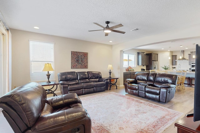 living room featuring visible vents, a ceiling fan, light wood-style flooring, a textured ceiling, and recessed lighting