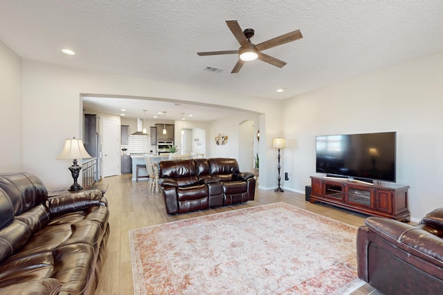 living room with recessed lighting, visible vents, a ceiling fan, a textured ceiling, and light wood-type flooring