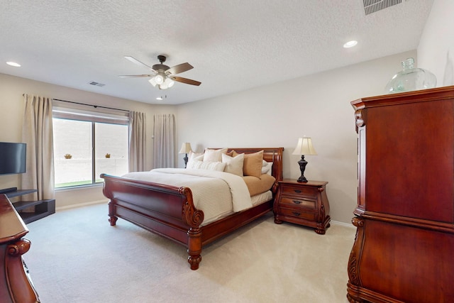 bedroom with light carpet, a textured ceiling, visible vents, and a ceiling fan