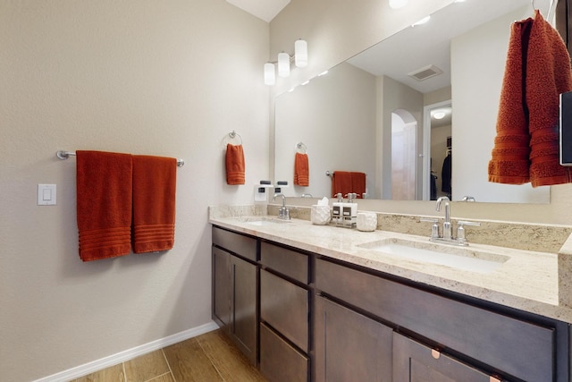 bathroom featuring baseboards, visible vents, a sink, and wood finished floors