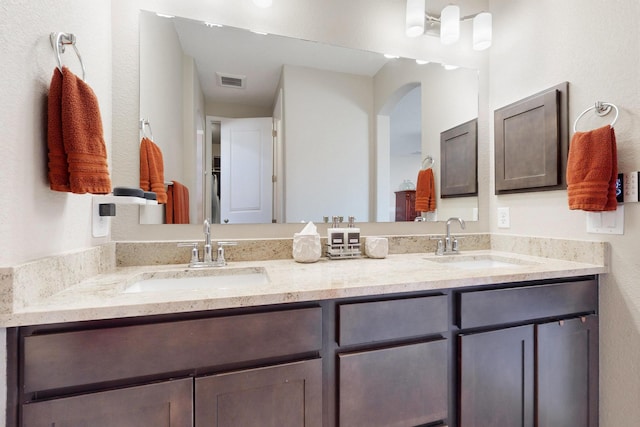 full bath with double vanity, a sink, and visible vents