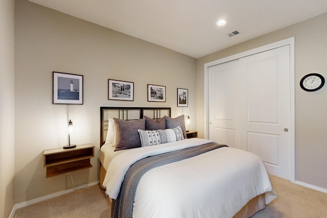 bedroom featuring a closet, light colored carpet, visible vents, and baseboards