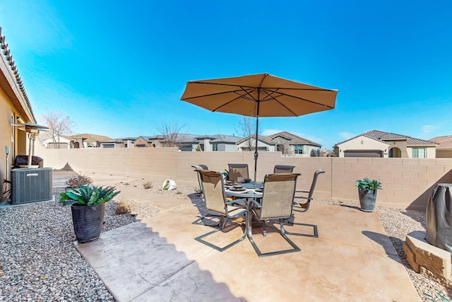 view of patio featuring a fenced backyard, a residential view, central AC, and outdoor dining space