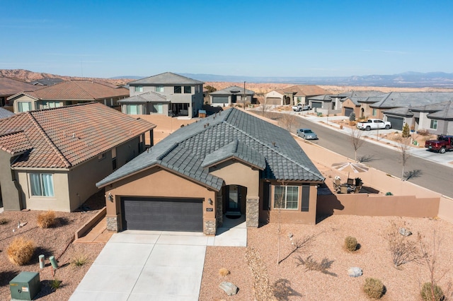 view of front facade featuring a garage, stone siding, concrete driveway, a residential view, and stucco siding