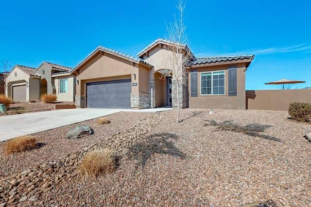 mediterranean / spanish home featuring driveway, stone siding, a tile roof, an attached garage, and stucco siding