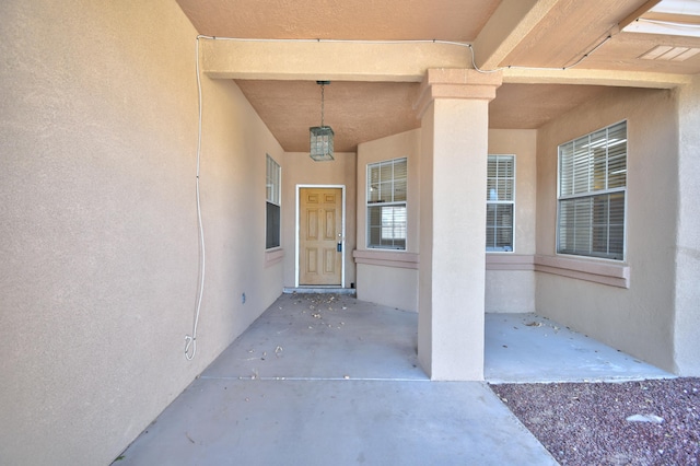 view of exterior entry with a patio area and stucco siding