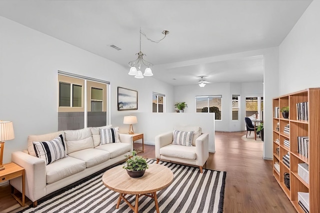 living area featuring an inviting chandelier, visible vents, and wood finished floors