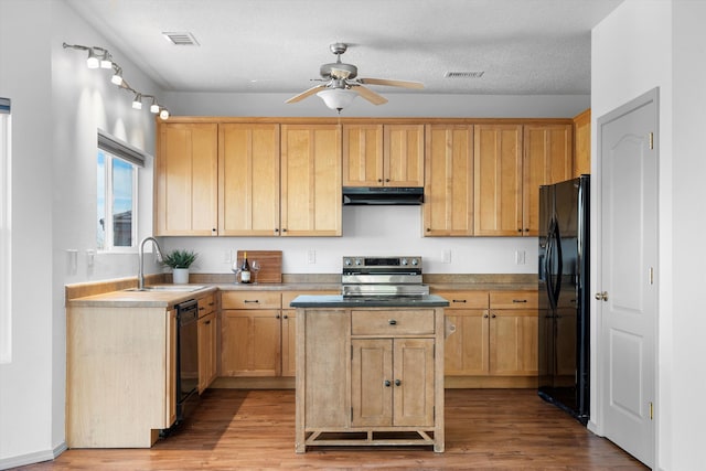 kitchen with under cabinet range hood, a kitchen island, a sink, visible vents, and black appliances