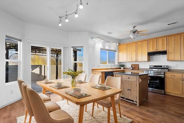 kitchen featuring black dishwasher, visible vents, wood finished floors, under cabinet range hood, and stainless steel range with electric stovetop