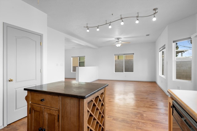 kitchen with a kitchen island, a ceiling fan, light wood-style floors, black dishwasher, and dark countertops