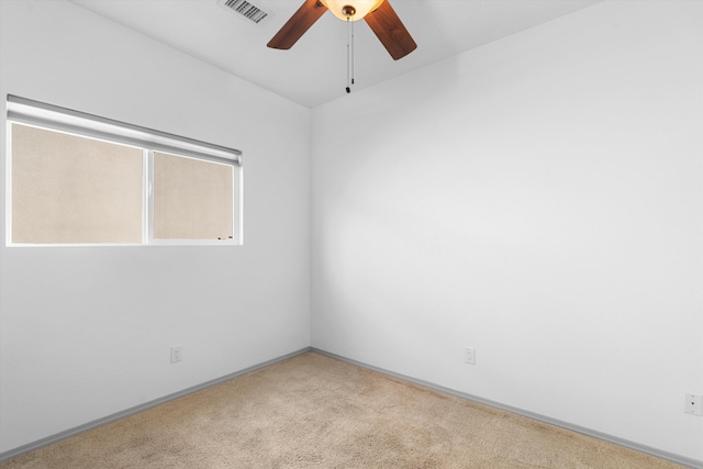 carpeted spare room with ceiling fan, visible vents, and baseboards