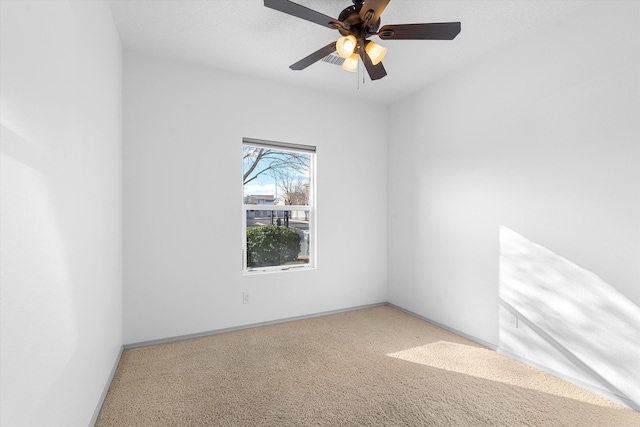 carpeted spare room featuring ceiling fan and baseboards