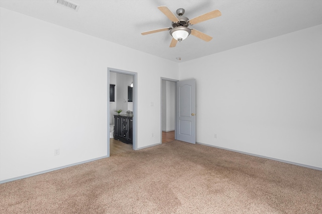 spare room featuring light carpet, ceiling fan, visible vents, and baseboards