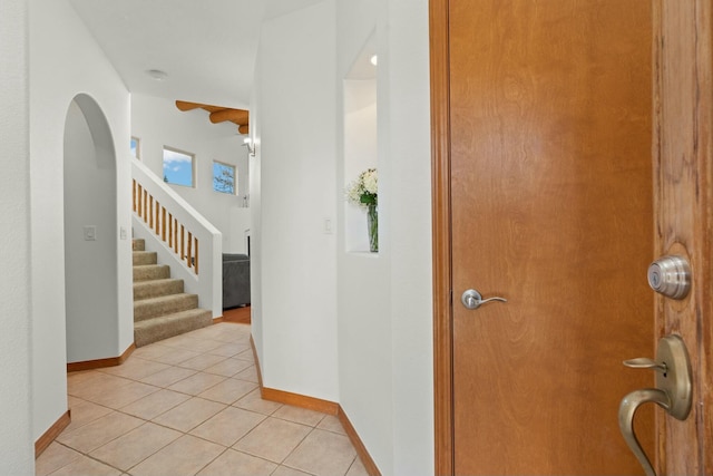 entryway with light tile patterned floors, stairway, and baseboards