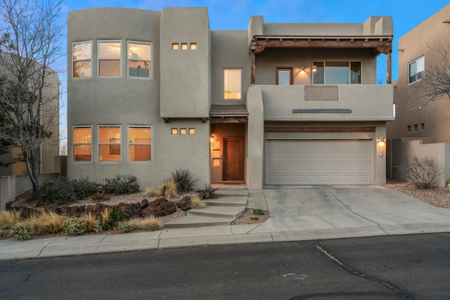 view of front of home with concrete driveway, an attached garage, and stucco siding