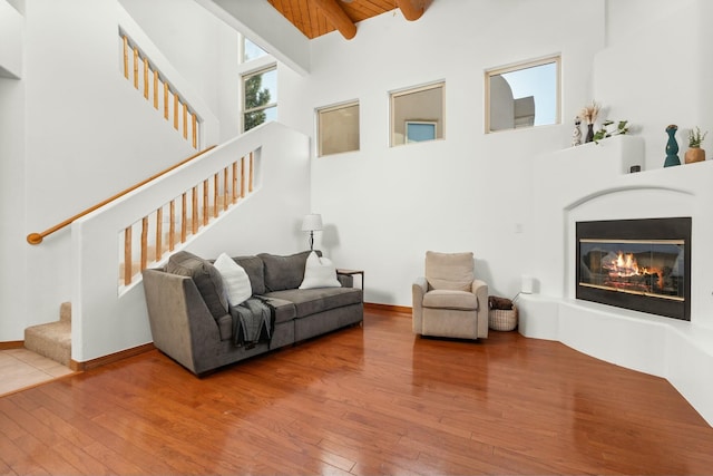 living area featuring stairway, beamed ceiling, wood-type flooring, and a towering ceiling