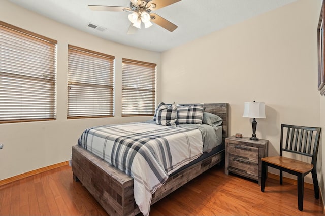 bedroom with visible vents, ceiling fan, baseboards, and wood finished floors