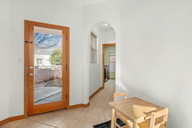 entryway featuring light tile patterned floors, arched walkways, and baseboards