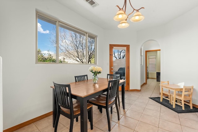 dining area featuring baseboards, visible vents, arched walkways, and a notable chandelier