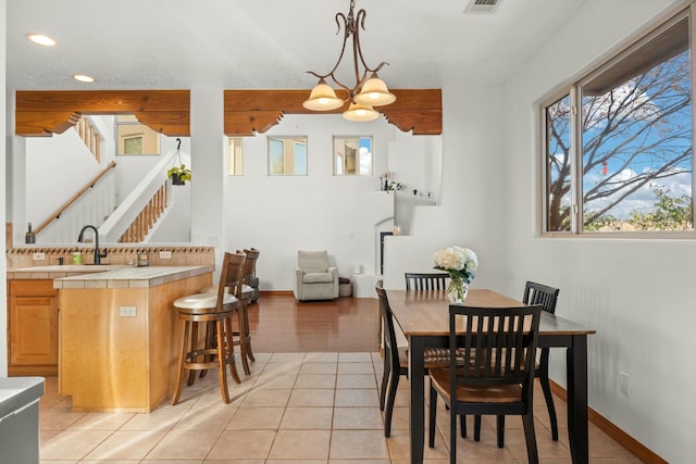 dining area with baseboards, stairway, light tile patterned flooring, and an inviting chandelier