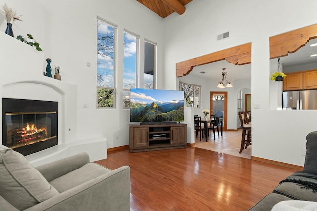 living room with arched walkways, wood finished floors, visible vents, baseboards, and a glass covered fireplace