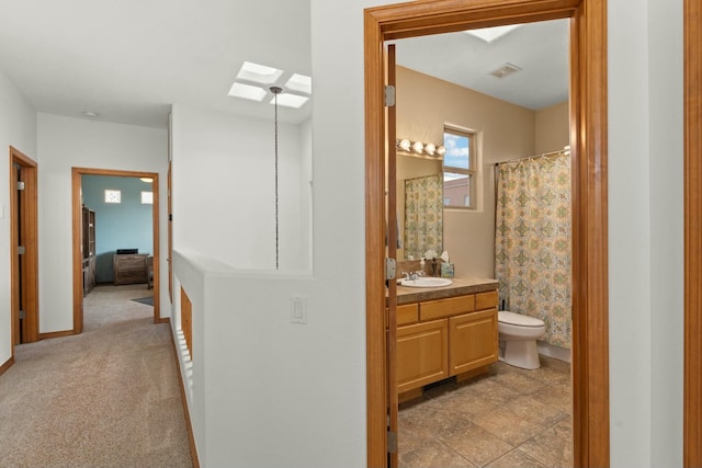 full bathroom with toilet, a skylight, visible vents, vanity, and baseboards