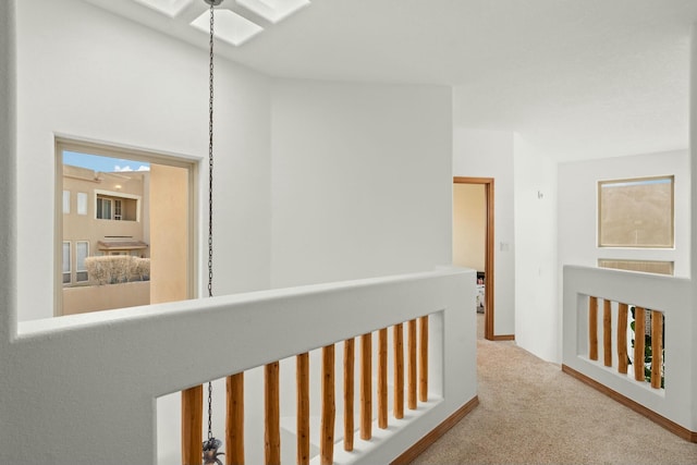 hall featuring a skylight, carpet flooring, and an upstairs landing