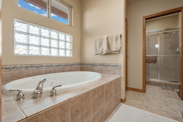 bathroom with tile patterned flooring, baseboards, a bath, and a shower stall