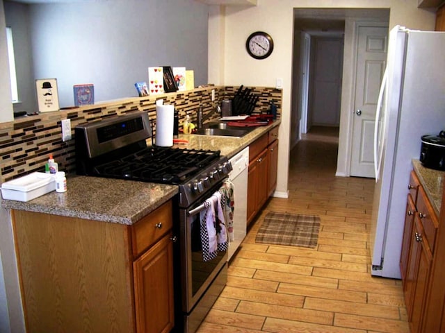 kitchen with white appliances, brown cabinets, a sink, light wood-style floors, and tasteful backsplash