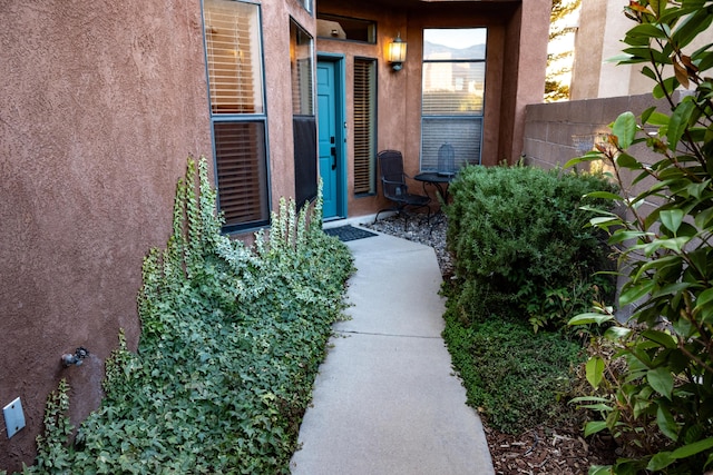 view of exterior entry featuring fence and stucco siding