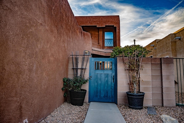 doorway to property featuring a gate, fence, and stucco siding