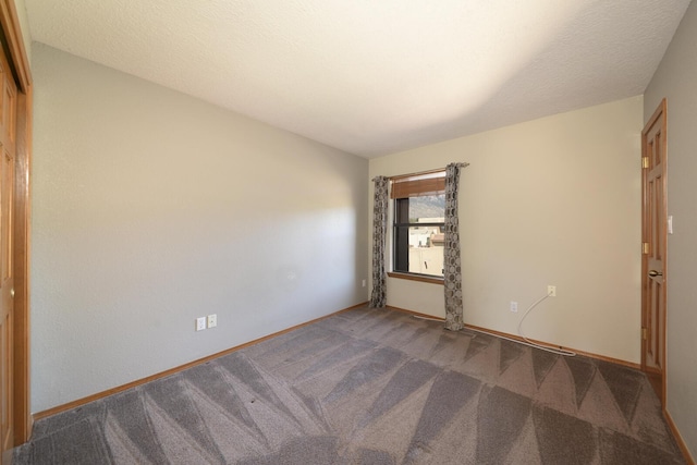 empty room with carpet, a textured ceiling, and baseboards