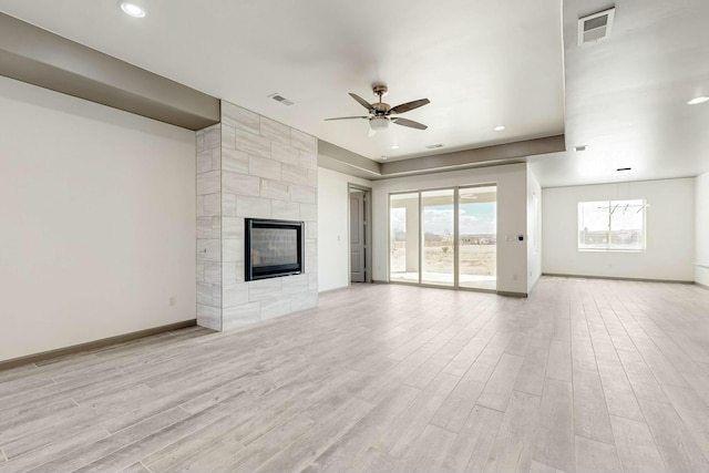 unfurnished living room with baseboards, light wood-style flooring, and a tiled fireplace