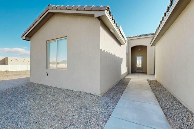 view of home's exterior featuring a patio area, fence, a tile roof, and stucco siding