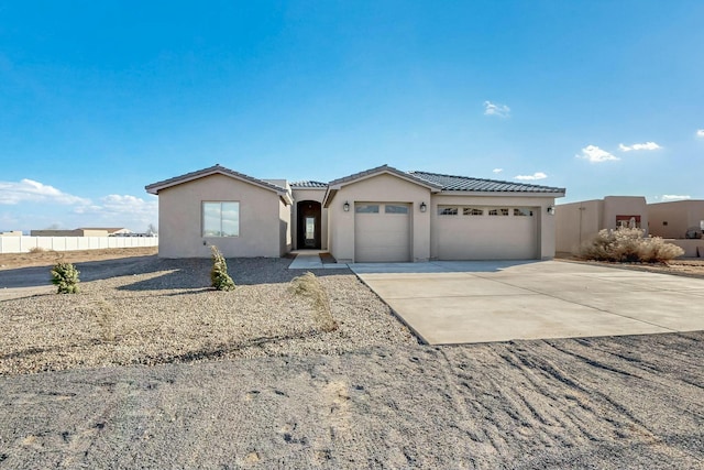 view of front facade with a garage, driveway, fence, and stucco siding