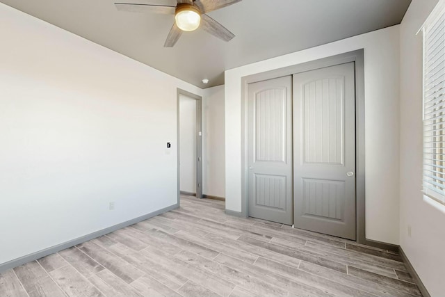 unfurnished bedroom featuring baseboards, ceiling fan, a closet, and light wood-style floors