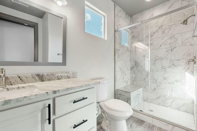 bathroom with a stall shower, vanity, toilet, and wood finished floors