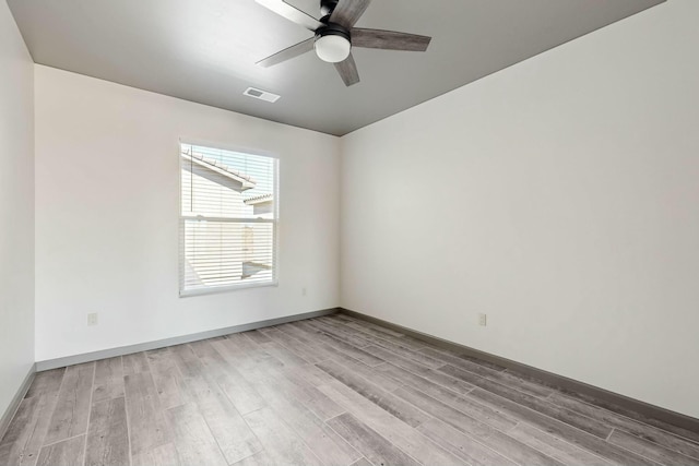 empty room featuring baseboards, ceiling fan, visible vents, and wood finished floors