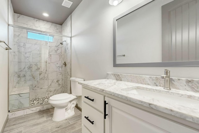 bathroom featuring visible vents, toilet, a stall shower, wood tiled floor, and vanity