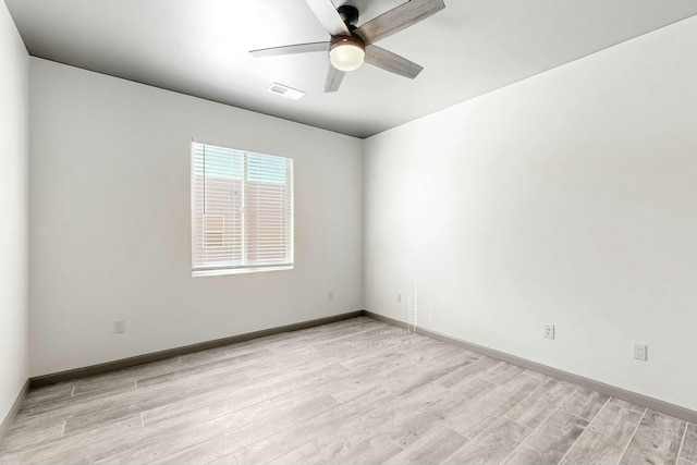 empty room with baseboards, visible vents, ceiling fan, and light wood finished floors