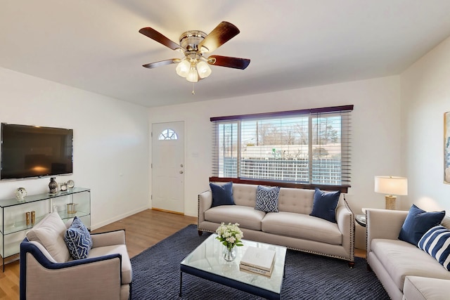 living area featuring ceiling fan, light wood-style flooring, and baseboards